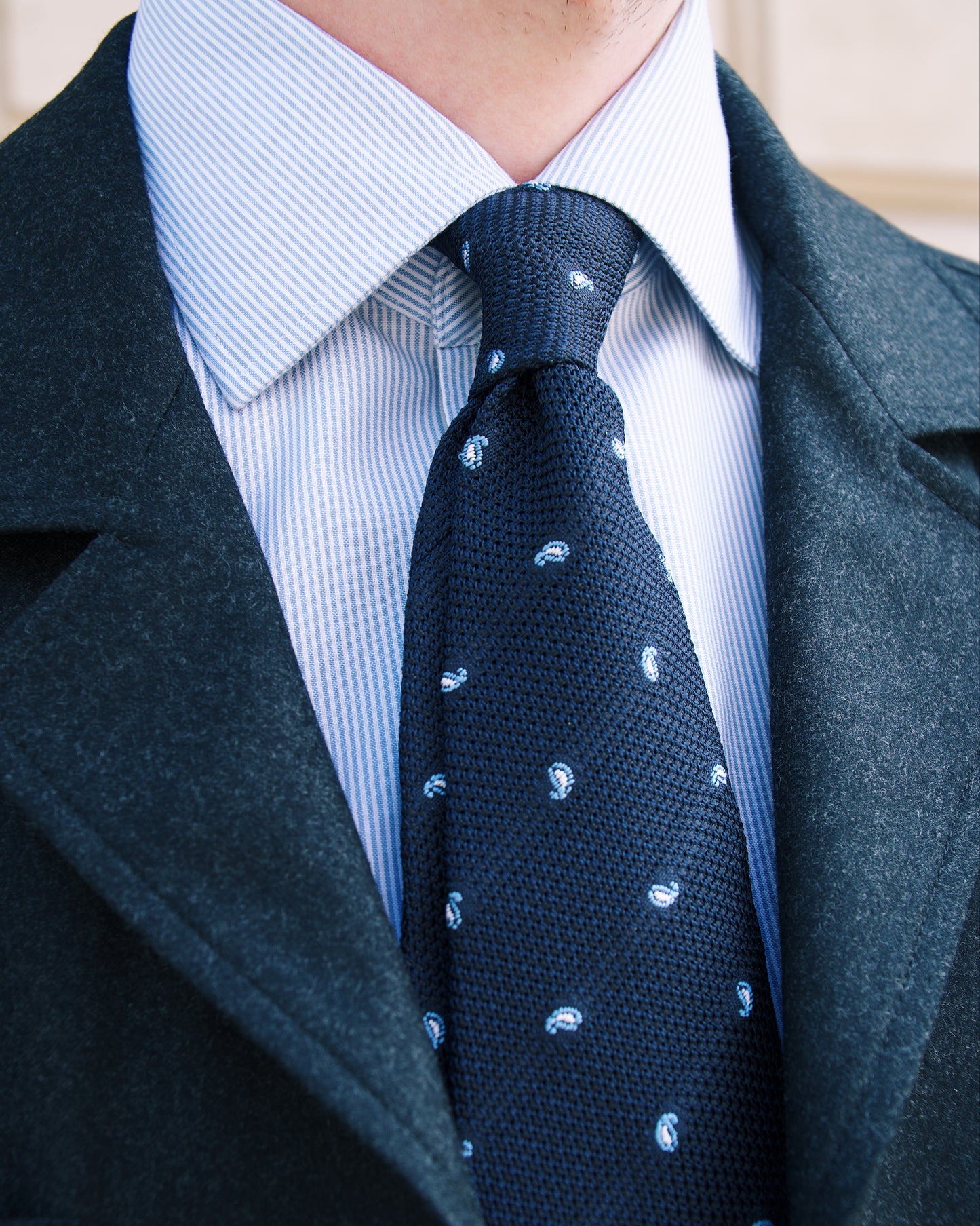 Mann trägt dunkelblaue Grenadine-Krawatte mit Paisley-Muster zu Business-Outfit