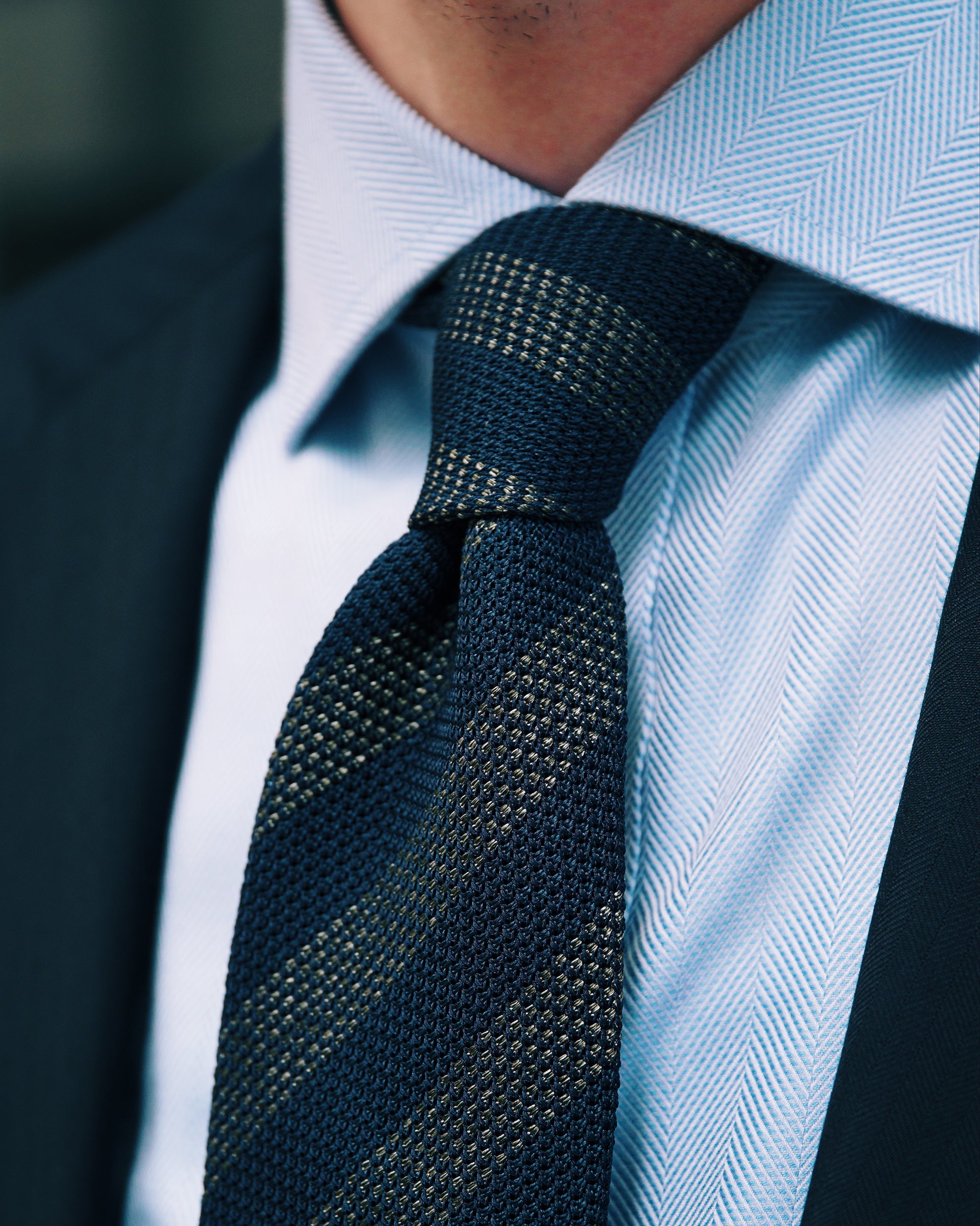 Mann trägt navy-goldene Regimentsstreifen-Krawatte zu hellblauem Hemd und Anzug